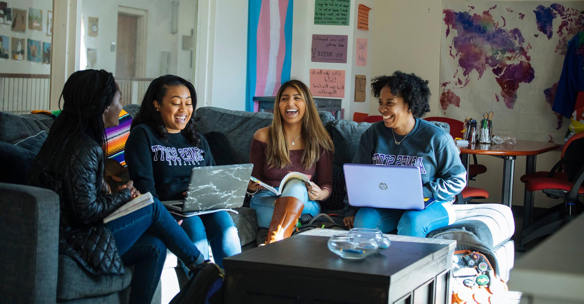 four students on a couch studying and laughing